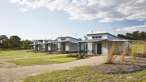 A row of single-story mobile homes with attached porches, set in a grassy area with a clear sky. - Ridgemill Escape (Broadwater)