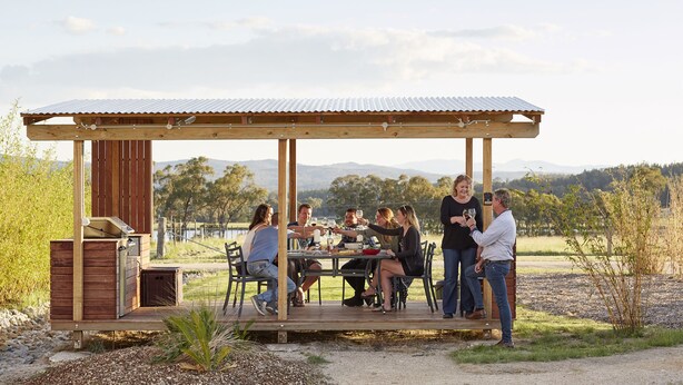 A wooden outdoor dining area with a metal roof, surrounded by natural landscape. - Ridgemill Escape (Broadwater)