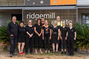 A group of people standing in front of a building with a sign that reads "ridgemill".