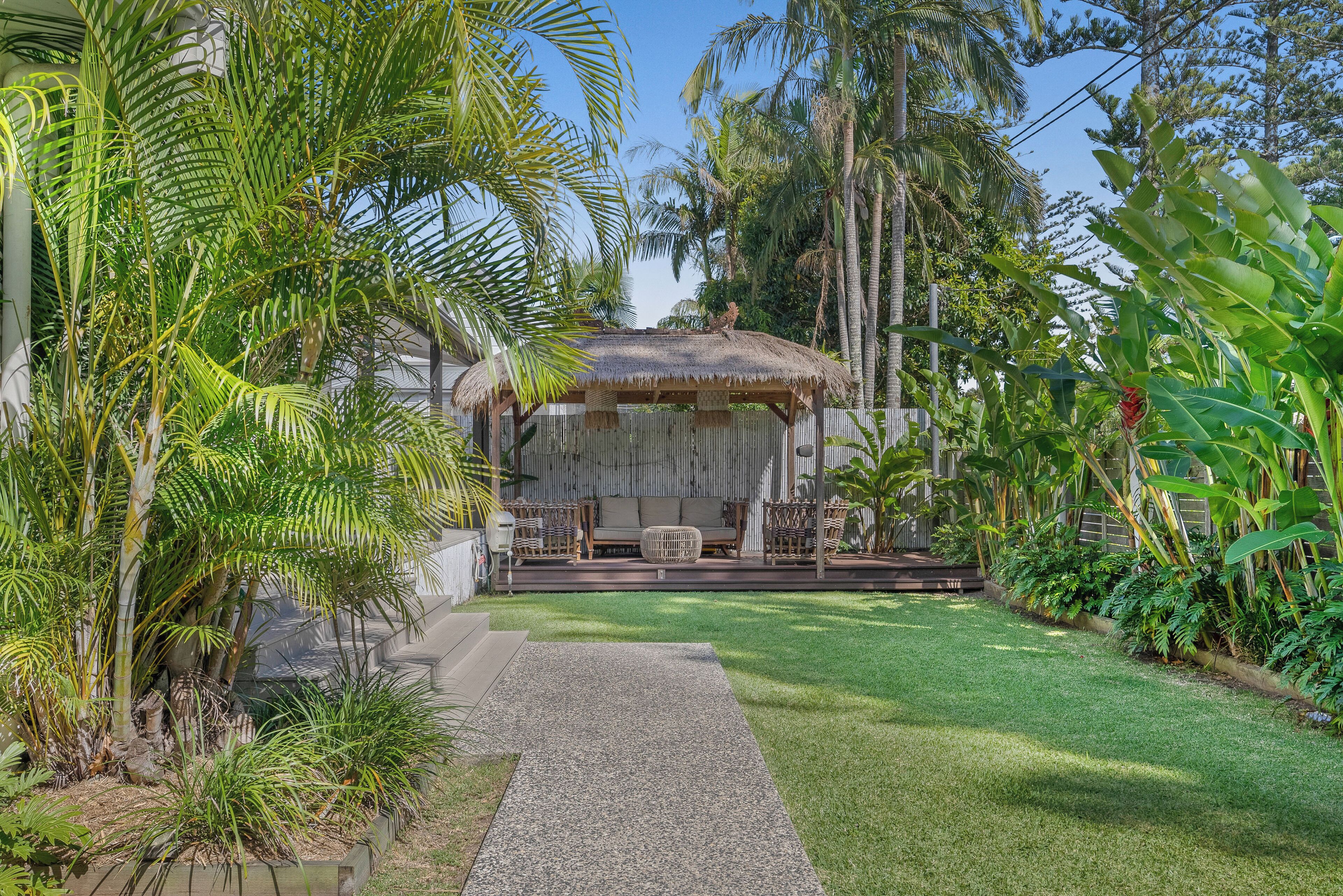 A thatched-roof hut with a seating area, surrounded by lush tropical vegetation.