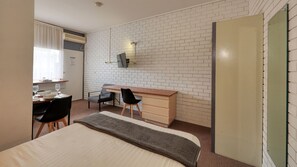 A hotel room with a bed, a desk, two chairs, a wardrobe, and a window with curtains. - Sun Centre Motel (Swan Hill)