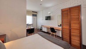A hotel room with a bed, a desk with a chair, a television mounted on the wall, and a wooden wardrobe. - Sun Centre Motel (Swan Hill)