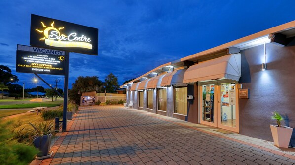 A motel named 'Sun Centre' with a 'VACANCY' sign, a 'FREE WIFI' sign, an 'IN-GROUND POOL' sign, and a 'COMPLIMENTARY FAMILY BBQ' sign. - Sun Centre Motel (Swan Hill)