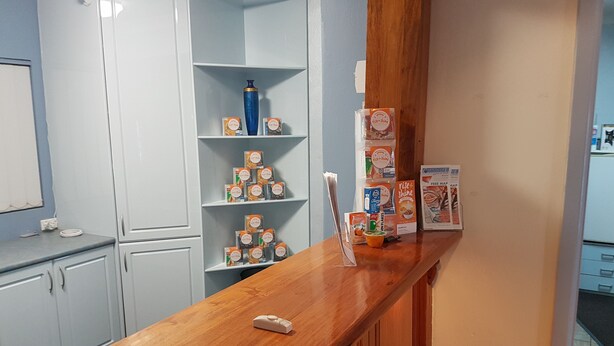 A kitchen with white cabinets, a wooden countertop, and various food items on shelves. - Acacia Motel Griffith (Griffith)