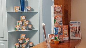 Ein Empfangsbereich mit Holztresen, Regalen voller Frühstücksprodukten, einer Vase und einer Kartenanzeige.