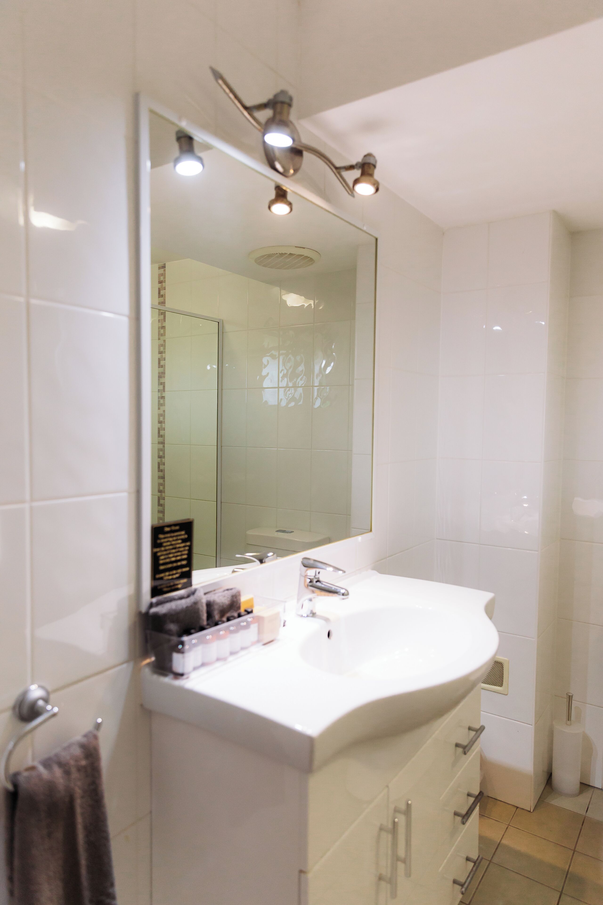 Un baño moderno con un espejo grande, un lavabo blanco y una zona de ducha.