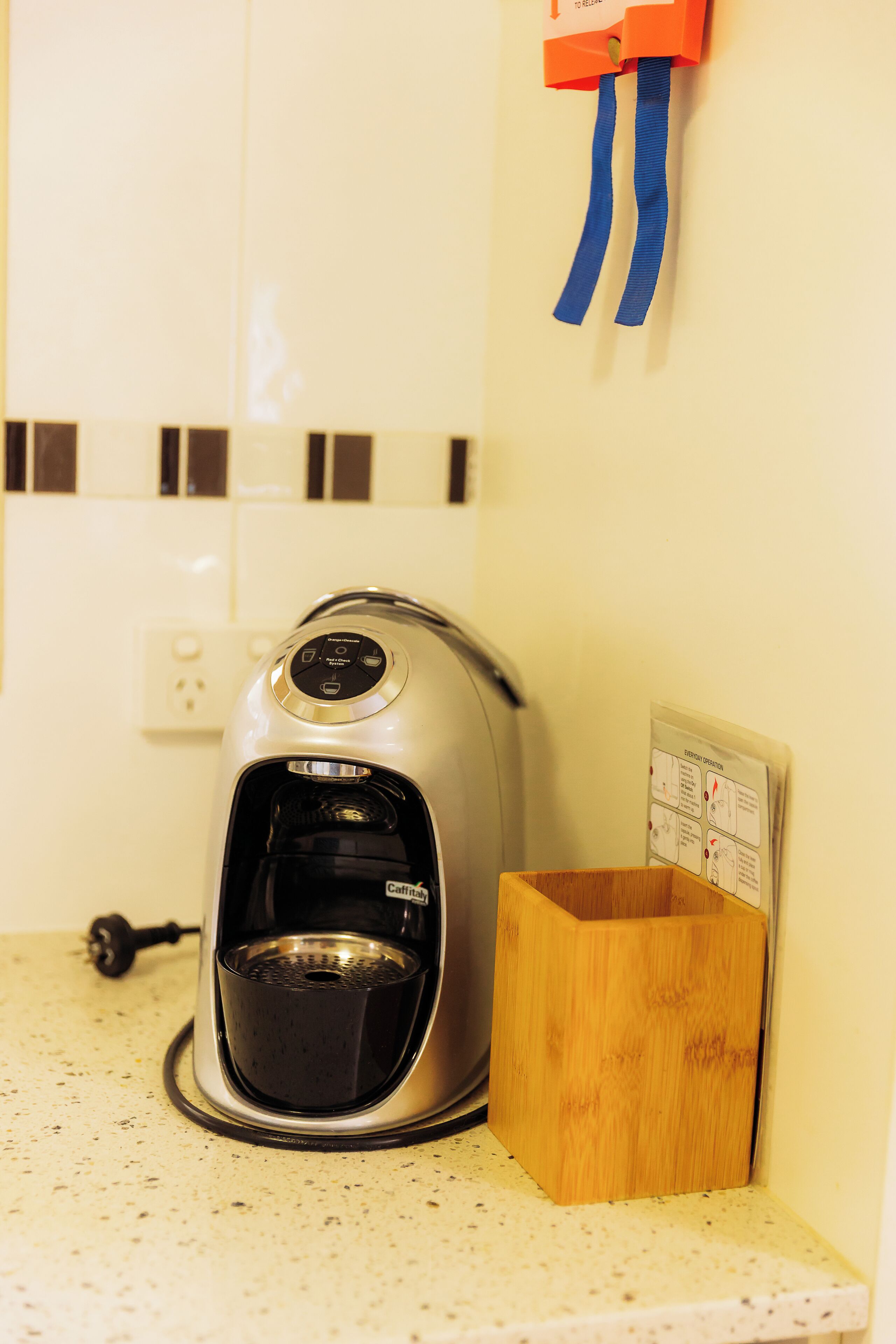 Una cafetera sobre una encimera de cocina con un caja de madera y un dispensador de pared.