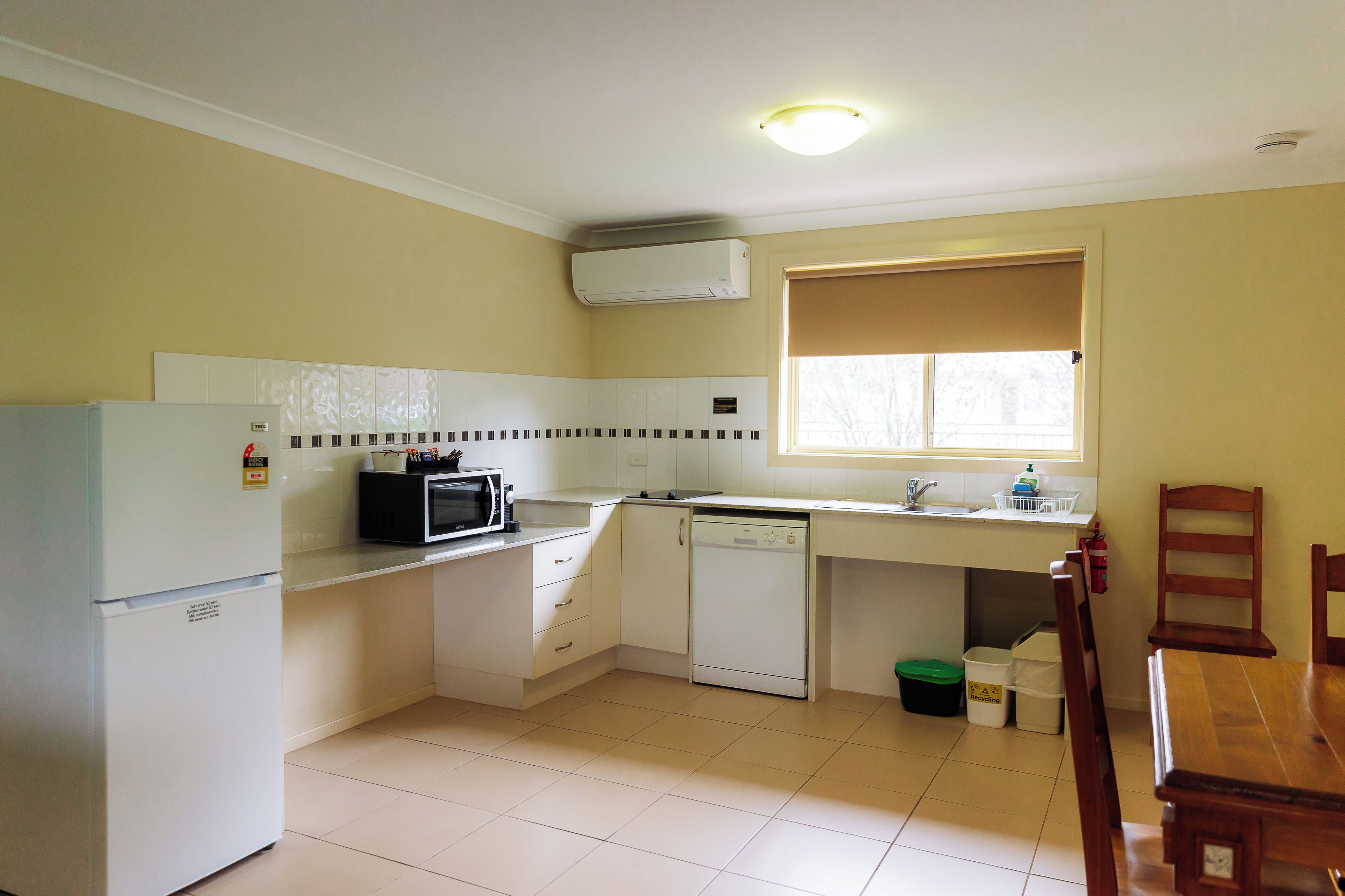 Una cocina compacta equipada con refrigerador, microondas, lavavajillas y una ventana sobre el fregadero.