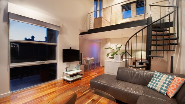 A modern living room with a leather sofa, a glass coffee table, and a large window. - Semaphore Blue Apartments (Semaphore)