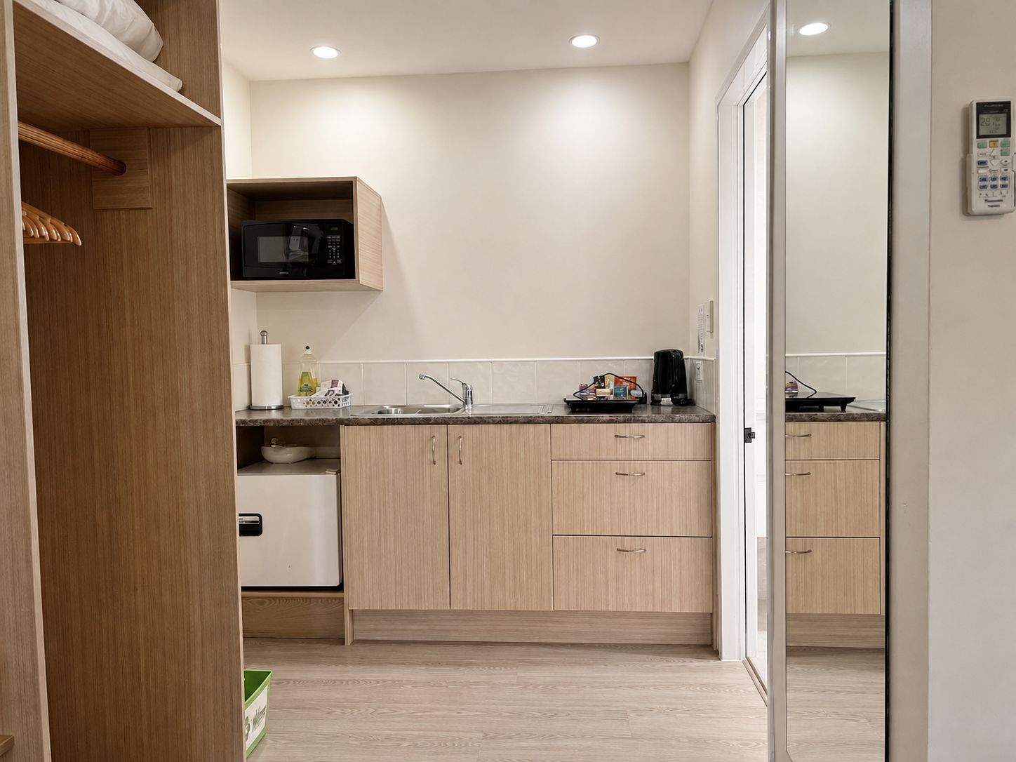 A modern kitchen with wooden cabinets, a microwave, and a coffee maker.