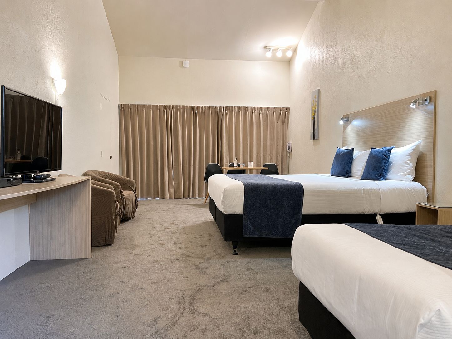 Ein Hotelzimmer mit einem Bett, einem Schreibtisch mit Fernseher und einem großen Fenster mit Vorhängen.
