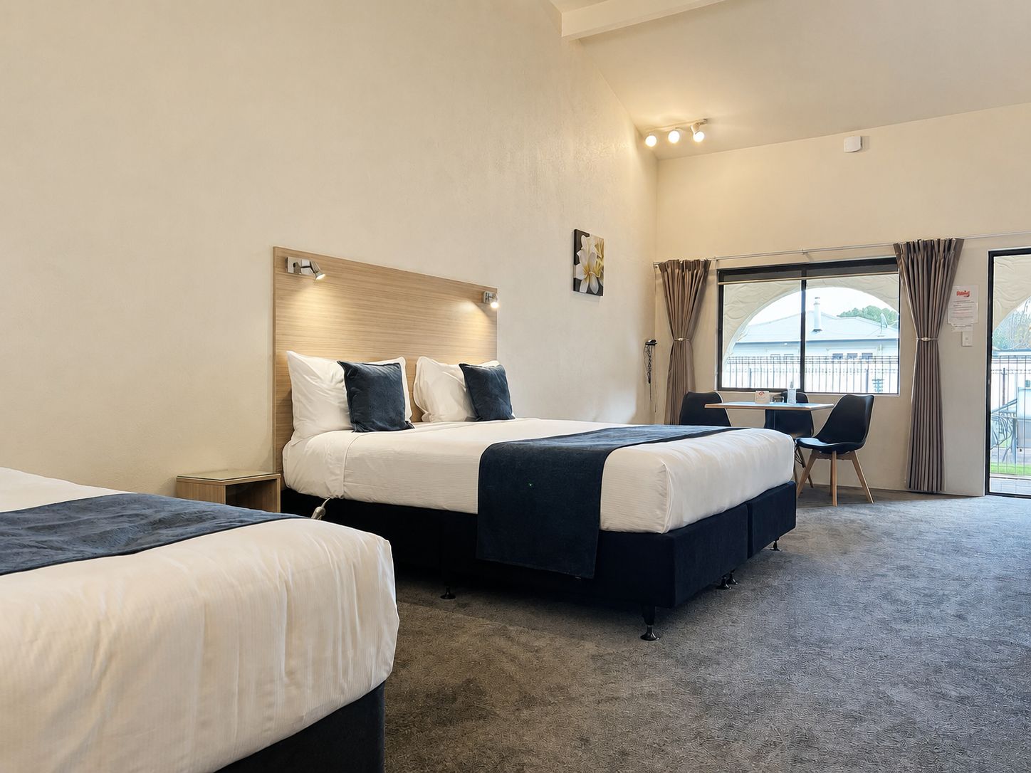 A hotel room with a bed, a chair, a desk, and a window with curtains.