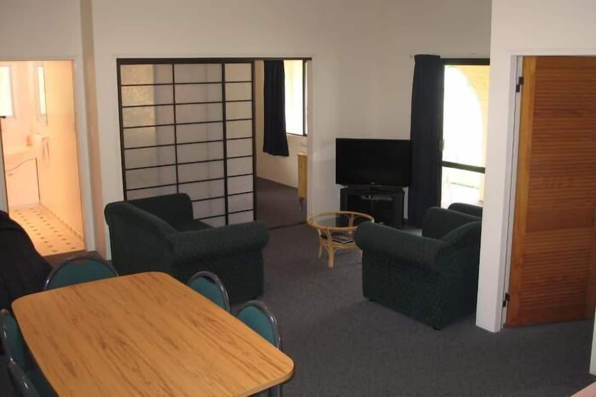 Un espacio habitable compacto con comedor, zona de estar con televisor y puerta corredera.