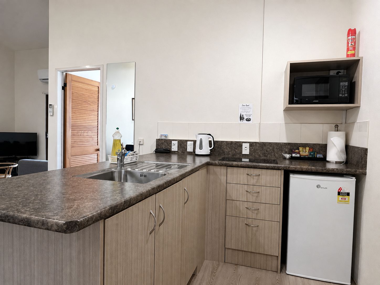 Una cocina moderna con microondas integrado, cafetera y refrigerador.