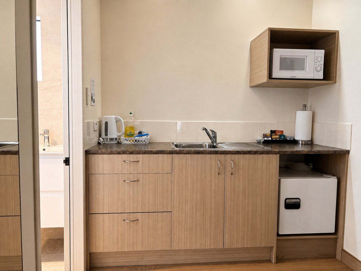 A compact kitchen with a microwave, sink, and a small refrigerator.