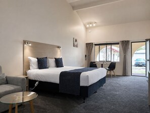 A hotel room with a bed, a sofa, a small table, and a window with curtains.