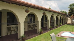 A building with a series of arches, outdoor seating, and a small pool. - Captains Quarters Motor Inn (Cambridge)