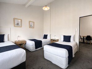 A hotel room with three beds, a desk, and a chair.