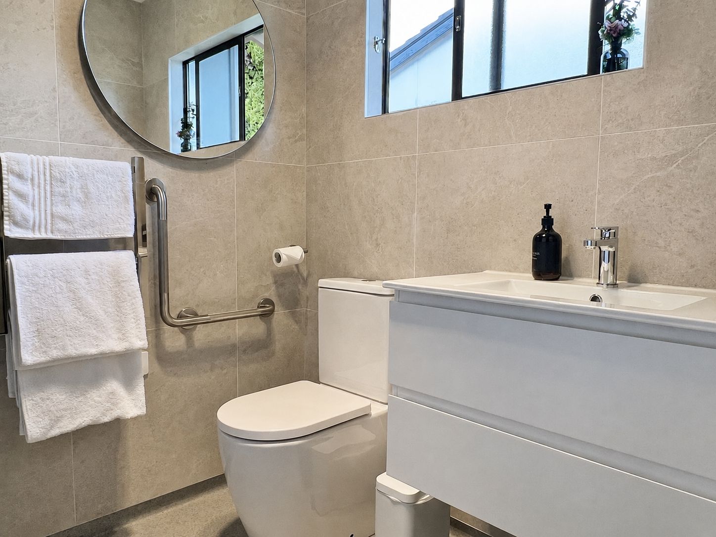 A bathroom with a toilet, a sink, a mirror, and a towel rack.