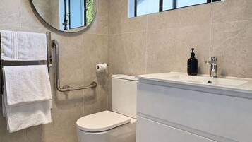 A bathroom with a toilet, a sink, a mirror, and a towel rack.