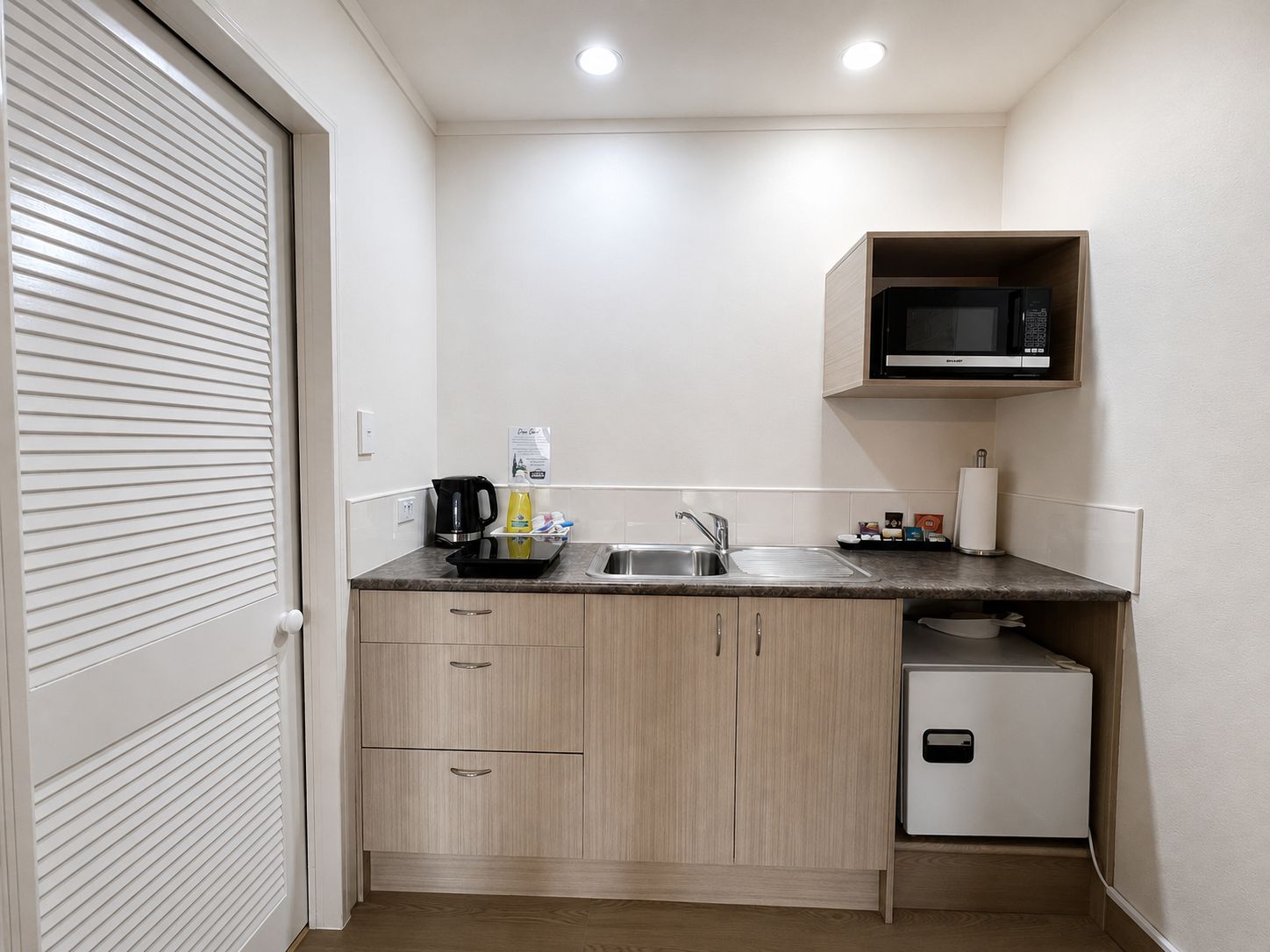 A compact kitchen with a microwave, sink, and a small refrigerator.