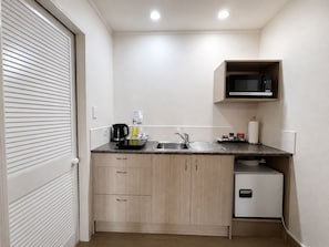 A compact kitchen with a microwave, sink, and a small refrigerator. - Captains Quarters Motor Inn (Cambridge)