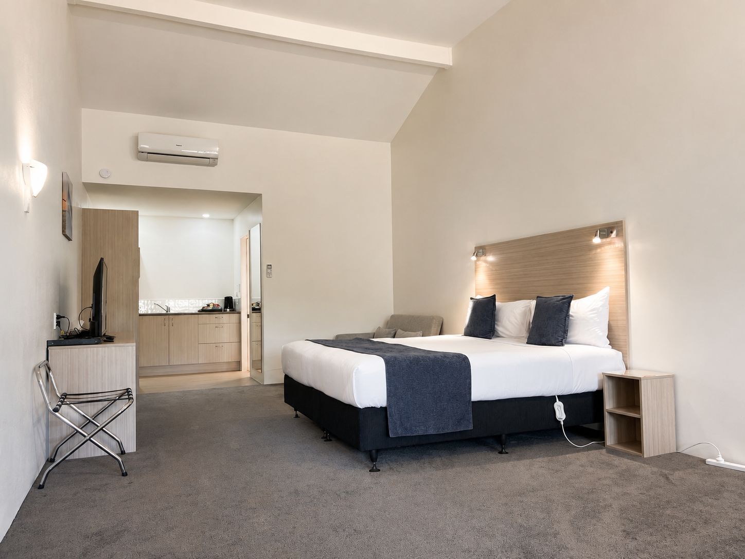 Una habitación de hotel moderna con una cama, una mesita de noche y un escritorio con una silla.