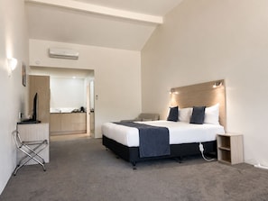 Una habitación de hotel moderna con una cama, una mesita de noche y un escritorio con una silla.