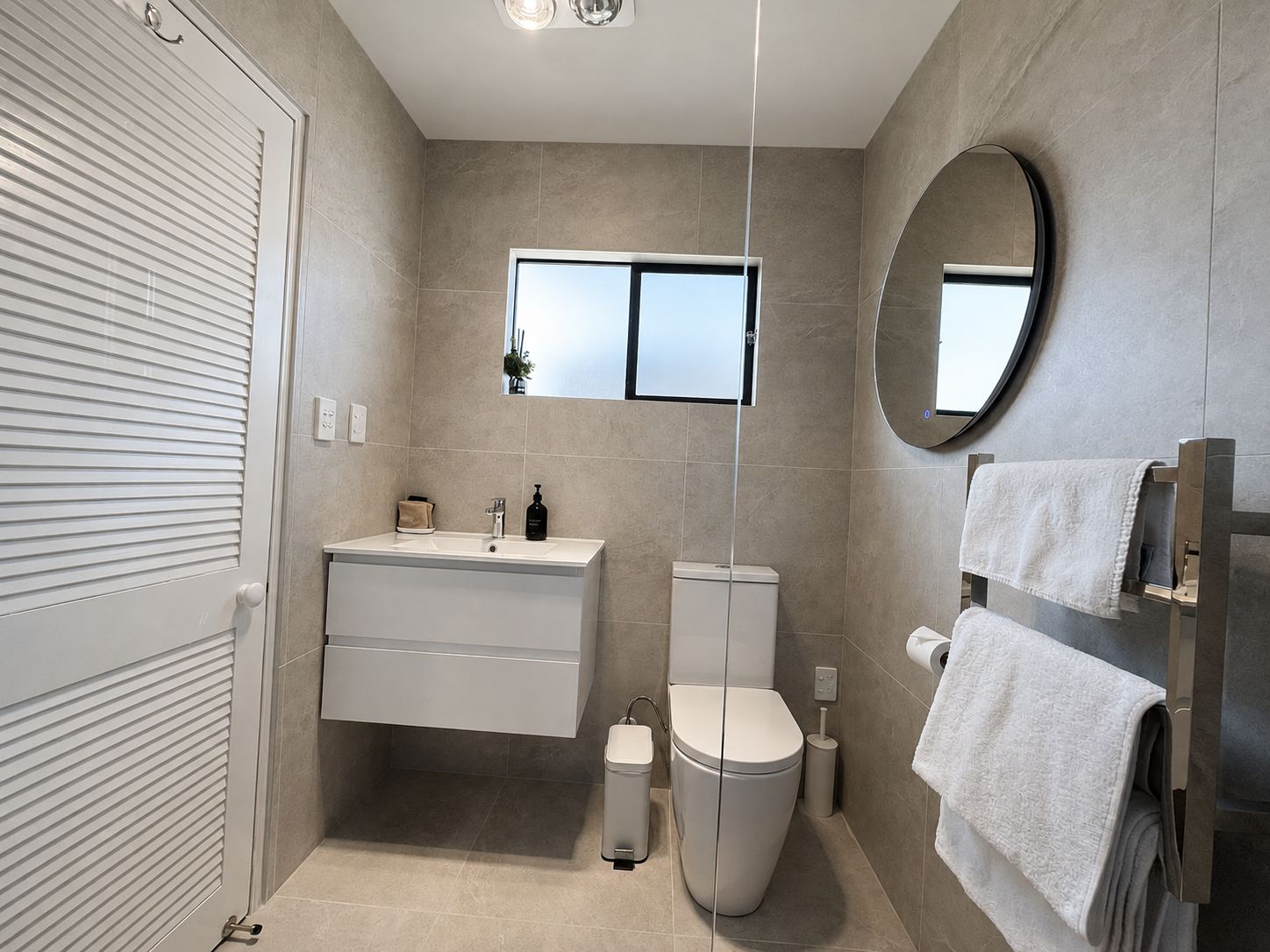 A modern bathroom with a toilet, sink, and mirror.