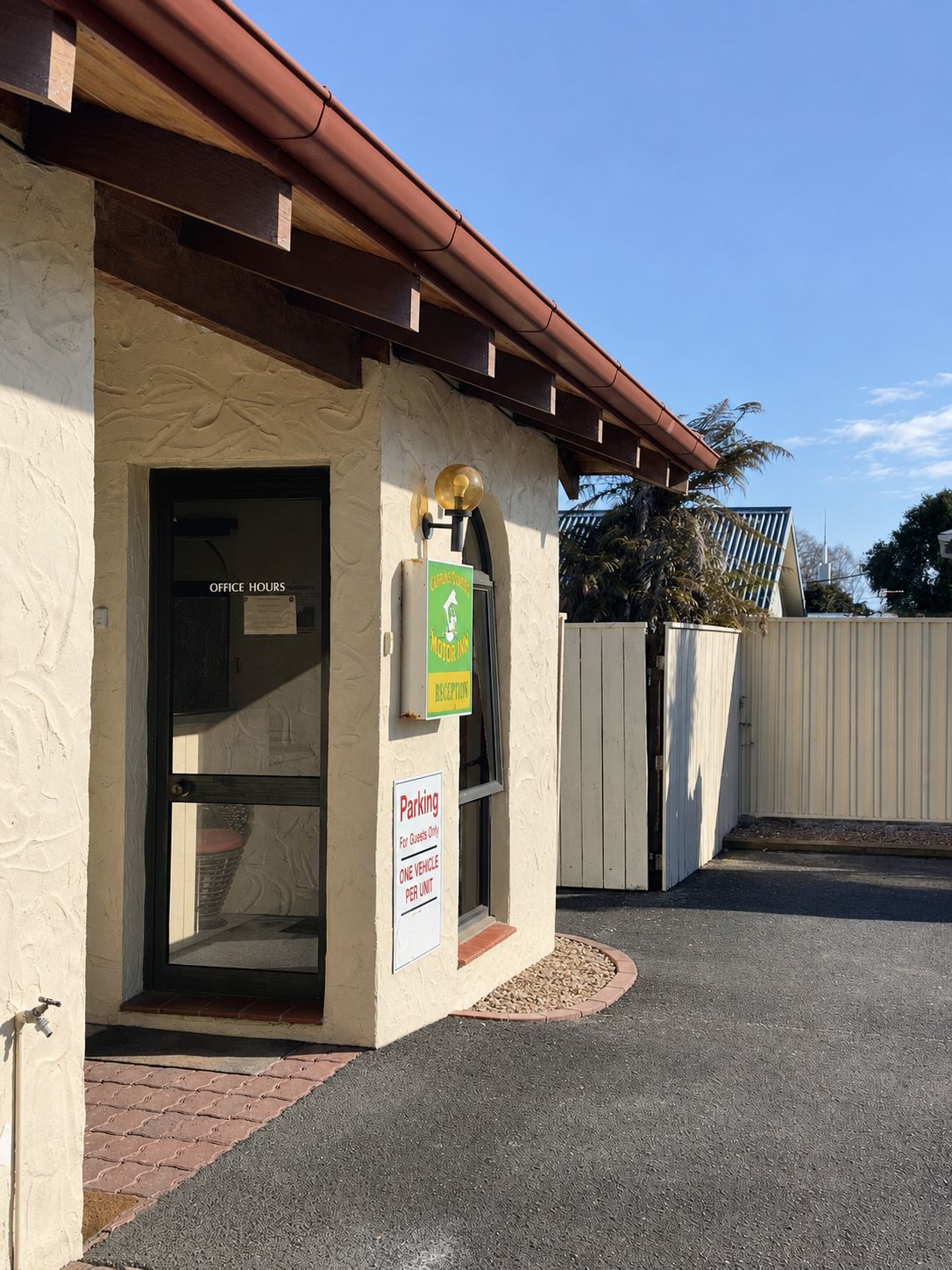 Entrada de un edificio con mostrador de recepción, señal de estacionamiento y letrero de motel.