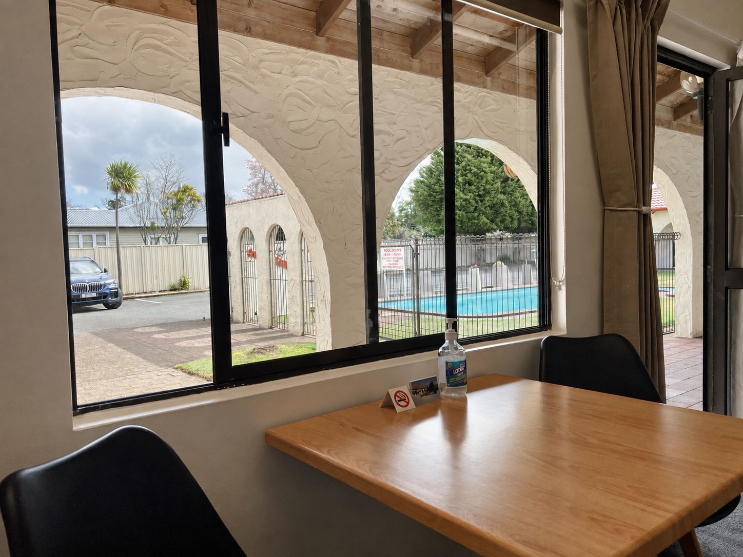 Habitación de hotel con vista a la piscina, una mesa de madera y una silla.