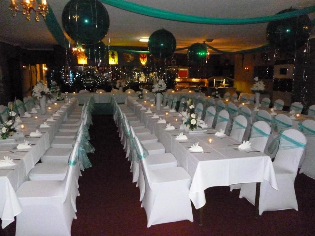 A banquet hall with rows of tables set for a formal event, each with white tablecloths and centerpieces.
