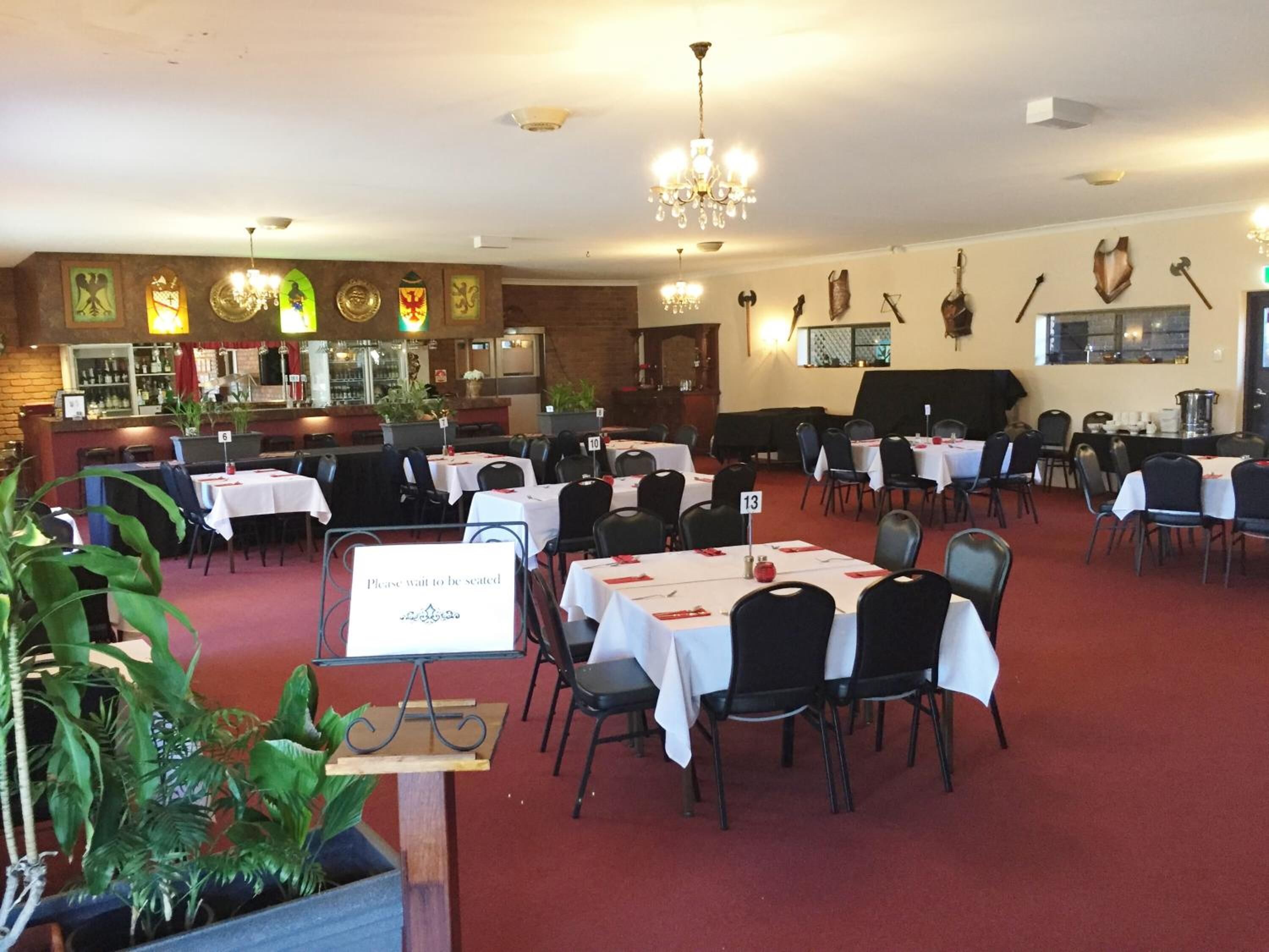 A restaurant with multiple tables and chairs, a bar area, and various wall decorations.
