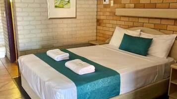 Een hotelkamer met een met baksteen patroon bedekte muur, een bed met witte lakens en een ingelijst schilderij aan de muur.