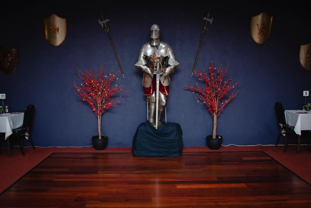 A room with a wooden floor, a table with a white tablecloth, and two potted plants with red foliage.