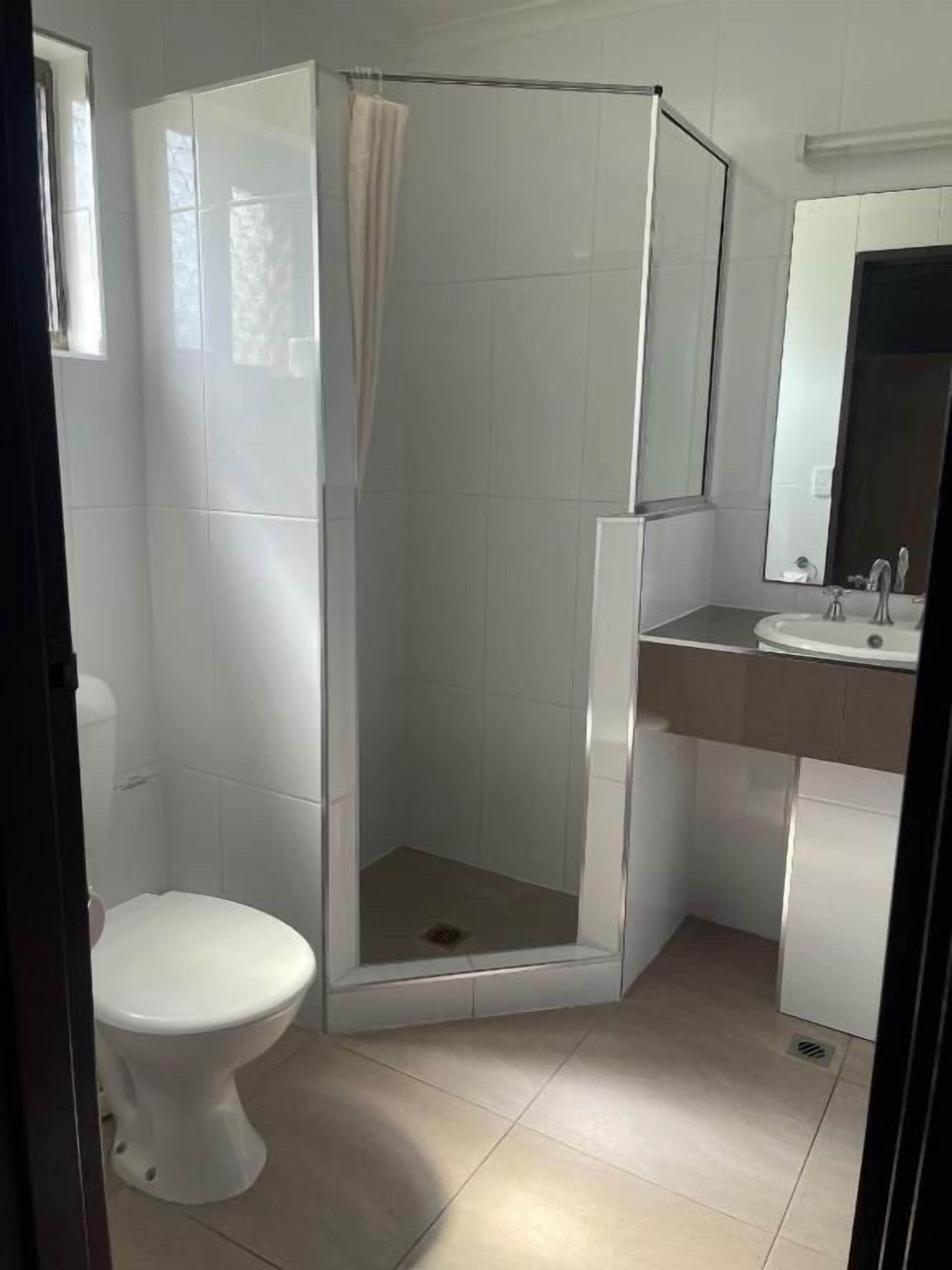 Une salle de bain comprenant des toilettes, un espace douche et un lavabo.