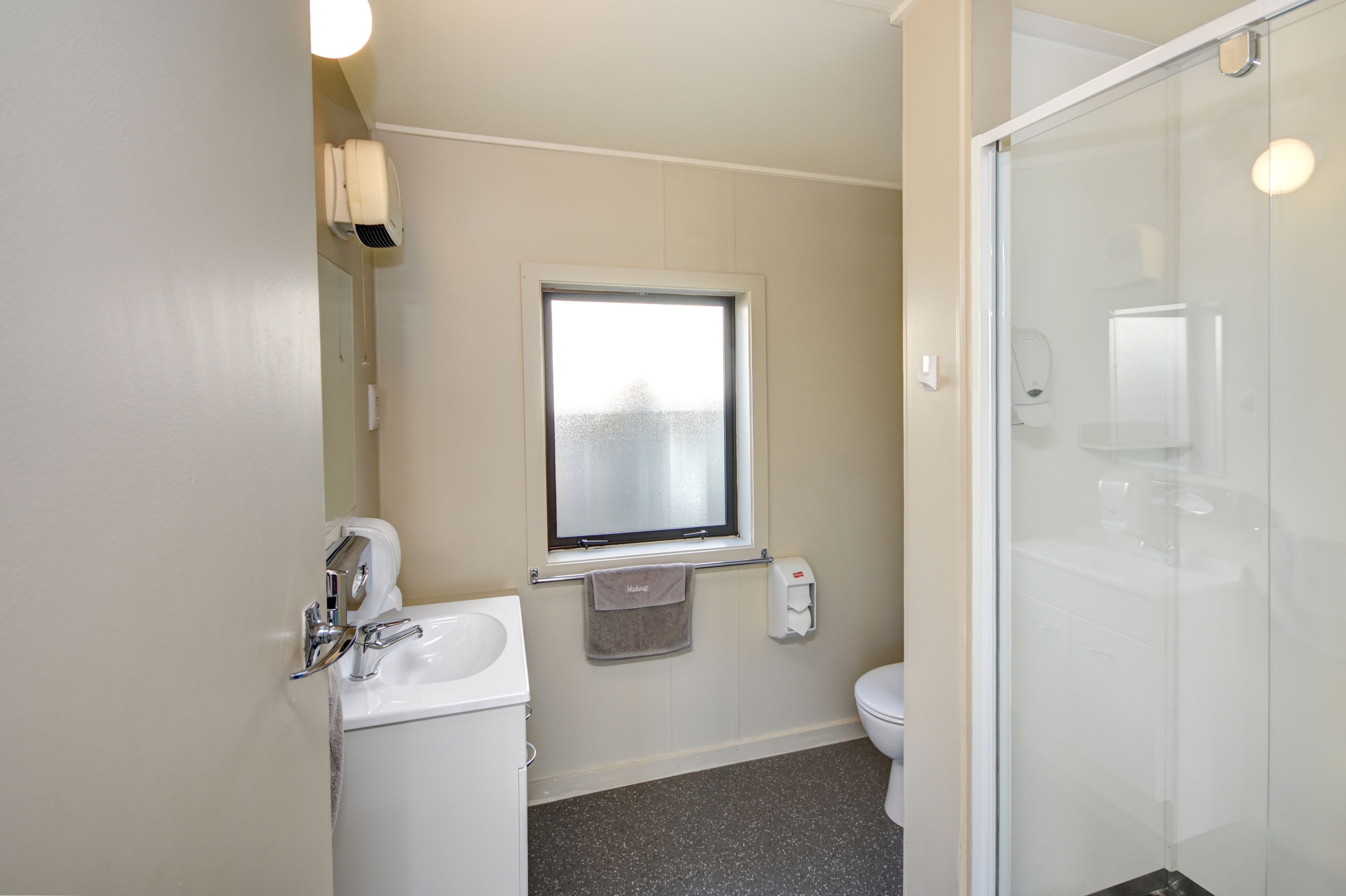 A bathroom with a toilet, sink, and a glass shower enclosure.