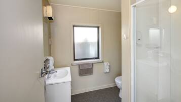 A bathroom with a toilet, sink, and a glass shower enclosure.