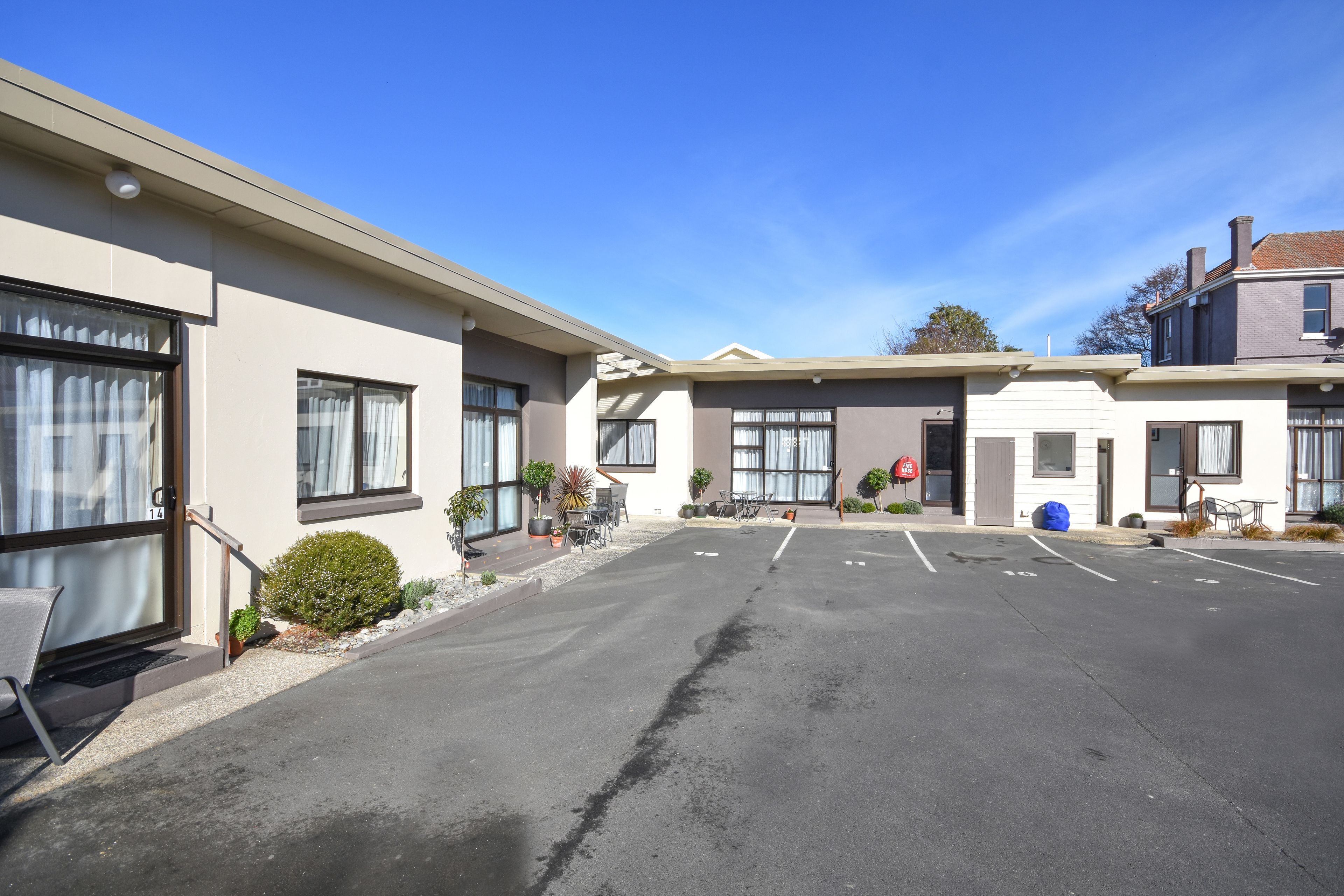 A building with a parking lot, outdoor seating, and a clear blue sky.