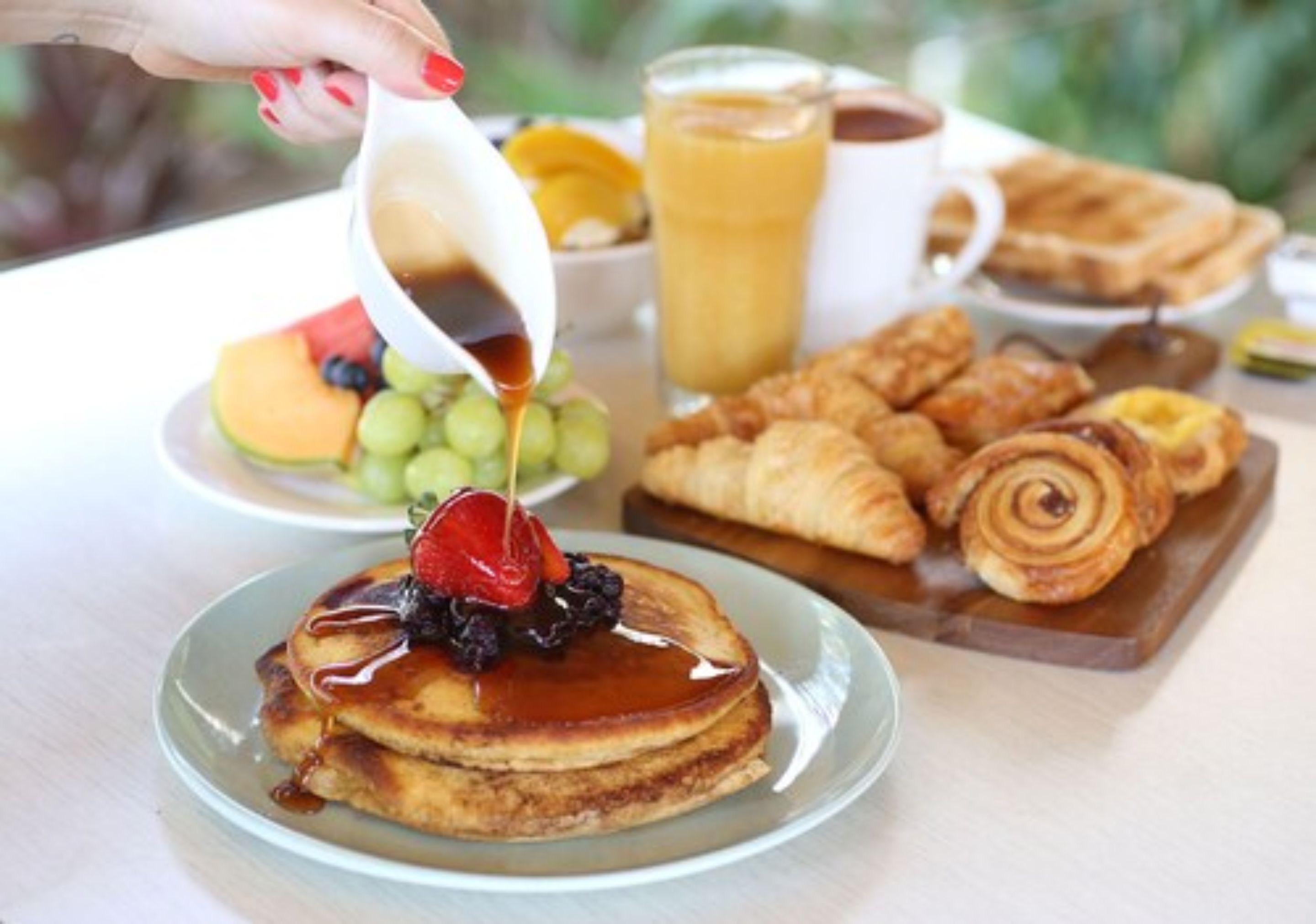 A breakfast setting with pancakes, croissants, and a fruit bowl.