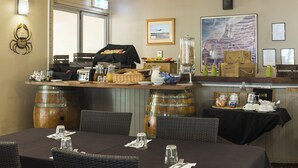 Un ristorante con zona bar, sedie in vimini e un tavolo apparecchiato per mangiare.