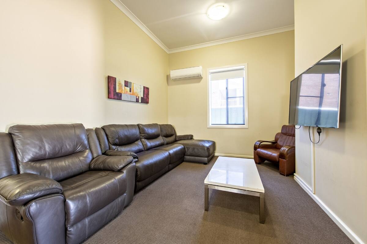 A living room with a sectional sofa, a coffee table, a TV, and a window.