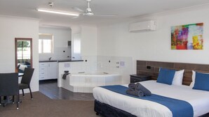 A hotel room with a bed, a desk, a chair, a bathroom with a bathtub, and a ceiling fan. - Matilda Motor Inn (Dubbo)