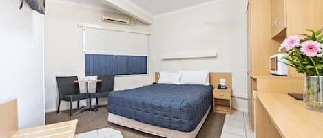 Una habitación de hotel moderna con una cama, un escritorio, una silla, un televisor y un ventilador de techo.