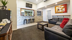 A modern lounge area with a bar, seating, and a stone accent wall. - Matilda Motor Inn (Dubbo)