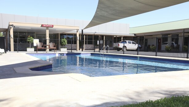 A swimming pool with a reception area and a covered seating area. - Matilda Motor Inn (Dubbo)