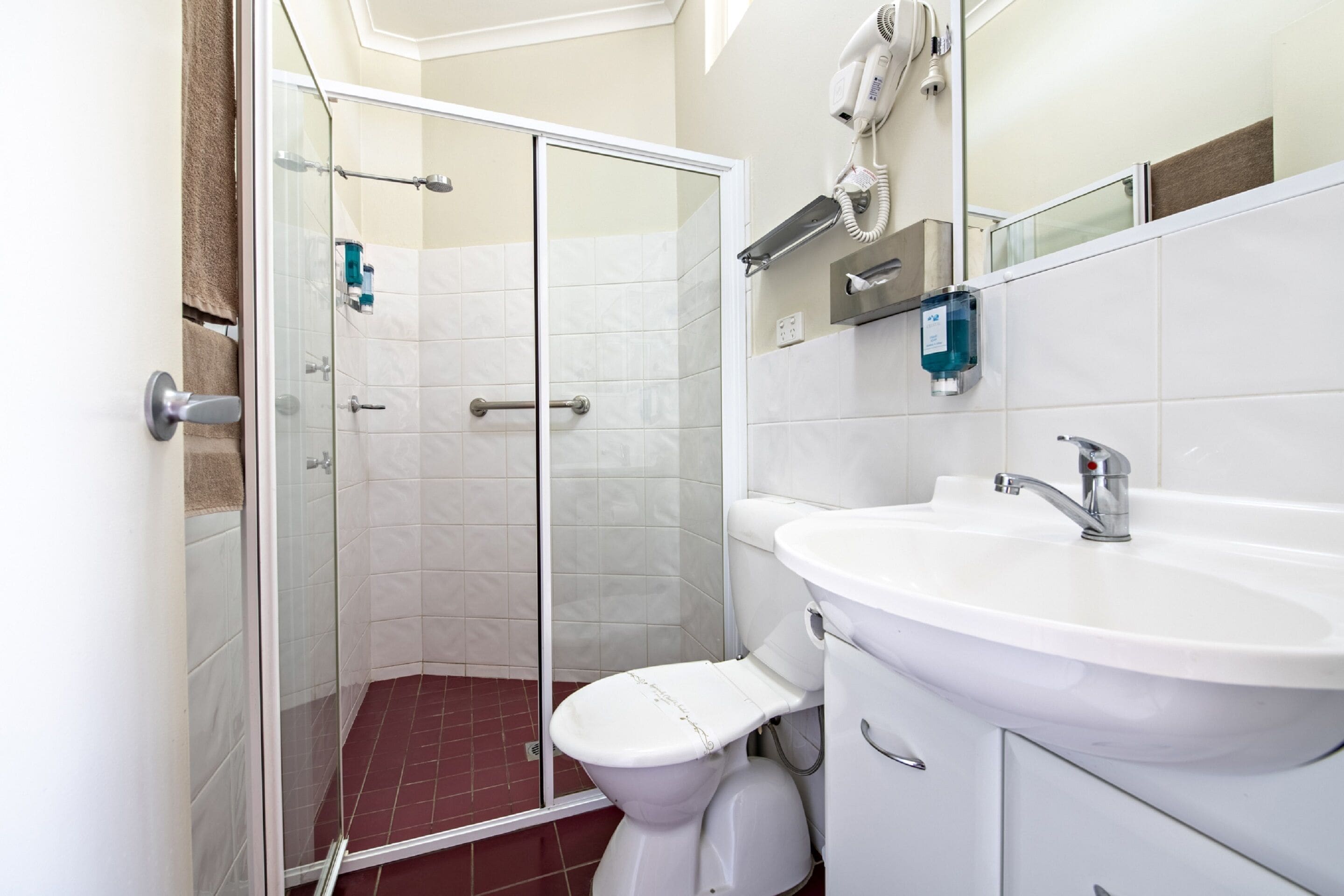 A modern bathroom with a glass shower enclosure, a white sink, and a toilet.