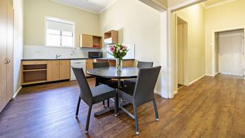 A modern kitchen with wooden cabinets, a dining table with chairs, and a vase with flowers.