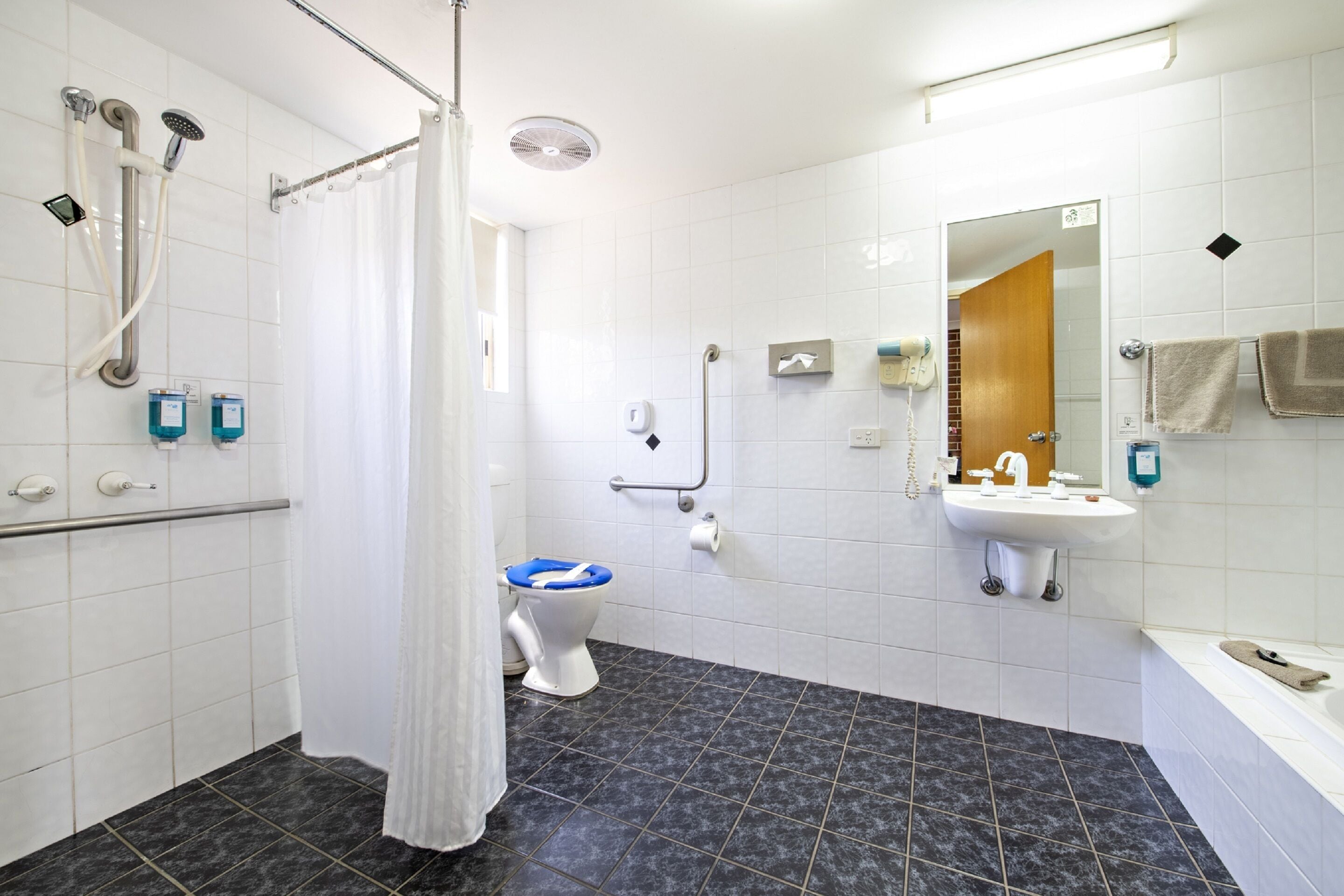Een moderne badkamer met douche, toilet, wastafel en spiegel.