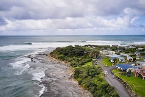 Une zone côtière caractérisée par un littoral rocheux, un petit village avec des maisons et une route, et l’océan en toile de fond.